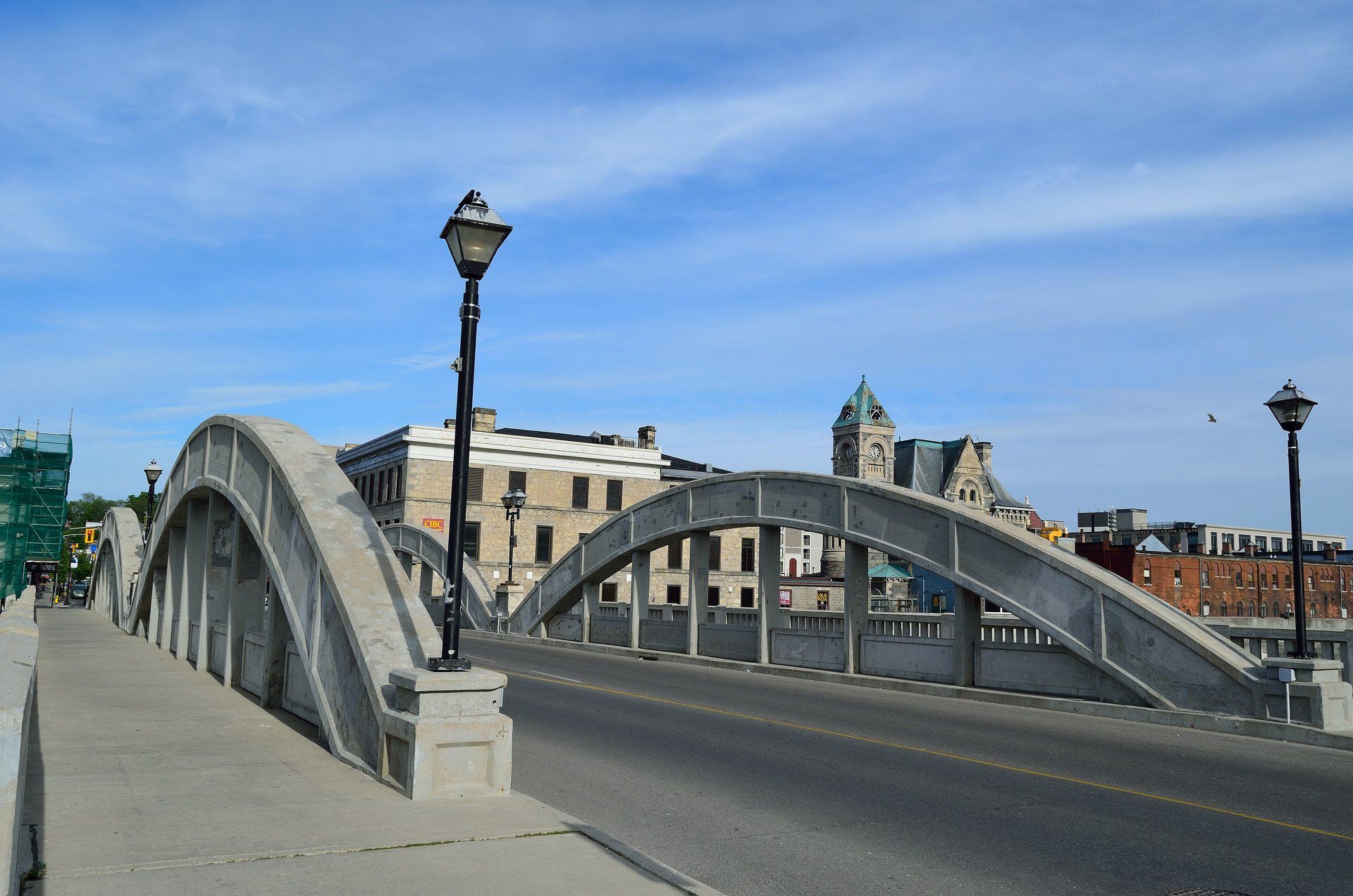 Concrete arches of the Main Street Bridge in Galt, Cambridge, with heritage stone buildings and a clock tower