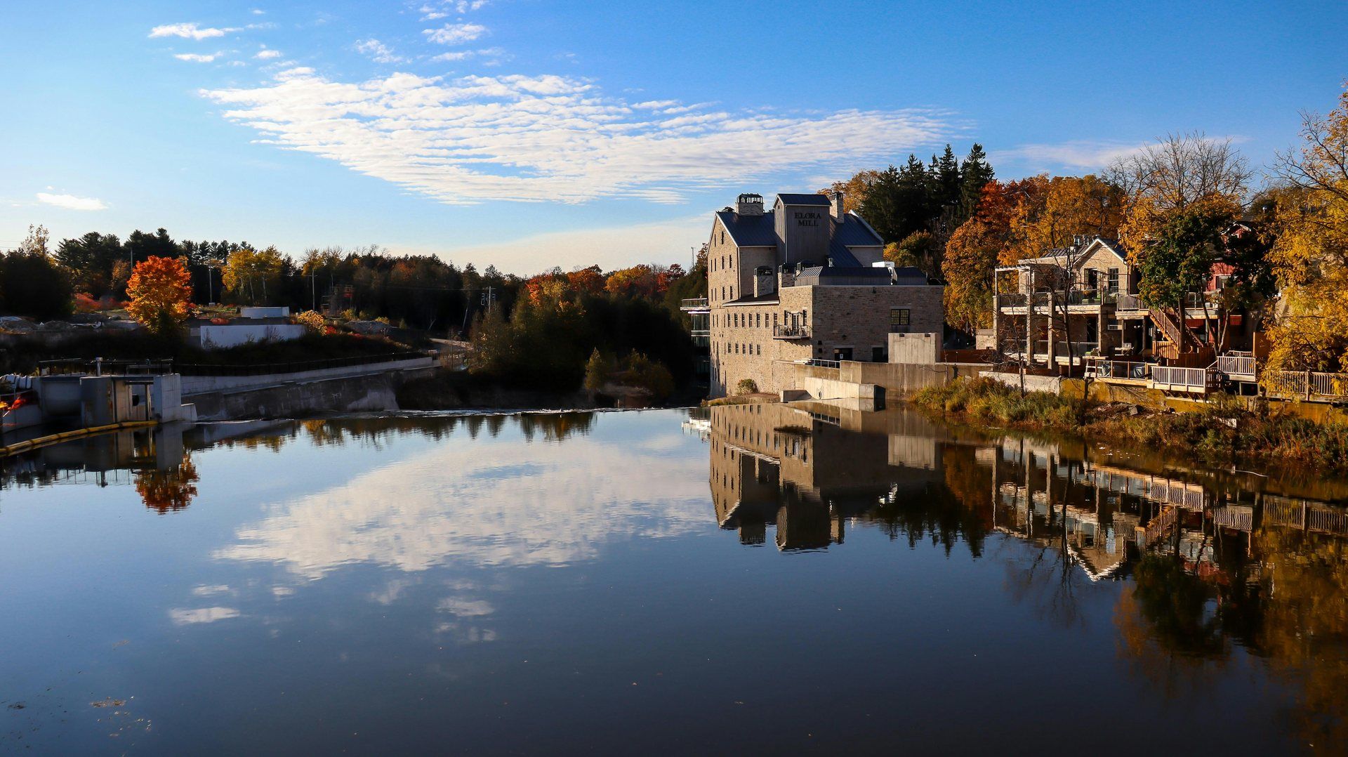 The stone Elora Mill on the Grand River, reflected in calm water with autumn trees